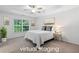 This virtually staged primary bedroom has a tray ceiling, ceiling fan, carpet flooring, and a large window at 651 Coligny Ct, Atlanta, GA 30350