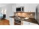 Modern kitchen features stainless steel appliances, granite countertops, white cabinetry and hardwood flooring at 651 Coligny Ct, Atlanta, GA 30350