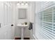 Bright powder room featuring a pedestal sink, modern fixtures, and window with natural light at 651 Coligny Ct, Atlanta, GA 30350
