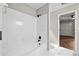 Bathroom with a white-tiled shower and tub adjacent to a bedroom with hardwood floors and a ceiling fan at 4528 Lashley Ne Ct, Marietta, GA 30068