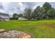 Large backyard showcasing green lawn with surrounding trees and stone patio feature at 520 White Pines Dr, Dallas, GA 30157