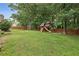 Lush green backyard featuring a swing set and mature trees, creating a serene and inviting outdoor space at 5349 Forest Springs Dr, Dunwoody, GA 30338