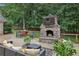 Outdoor living space with a stone fireplace, comfortable seating, and a grill, perfect for entertaining and relaxation at 5349 Forest Springs Dr, Dunwoody, GA 30338