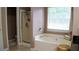 Bright bathroom featuring a large soaking tub and separate shower with natural light from an adjacent window at 1332 Chandler Cove Way, Grayson, GA 30017