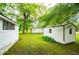 Large backyard with multiple outbuildings, surrounded by mature trees and green grass at 6539 E Strickland St, Douglasville, GA 30134