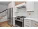 Modern kitchen with stainless steel appliances, white cabinets, and a stylish range hood at 1017 Mill Creek Ne Mnr, Brookhaven, GA 30319