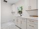 Bright laundry room with white cabinets, gold hardware, and marble-look tile floor at 1017 Mill Creek Ne Mnr, Brookhaven, GA 30319