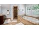 Bright bathroom featuring a soaking tub, glass shower, and travertine tile at 2941 Elizabeth Se St, Smyrna, GA 30080
