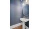 Stylish powder room with an oval mirror, pedestal sink, and blue textured wallpaper at 2941 Elizabeth Se St, Smyrna, GA 30080