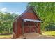 Rustic outbuilding featuring a quaint red exterior, a metal roof, and a brick driveway at 150 Henderson Farm Dr, Woodstock, GA 30188