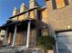 Brick townhome with boarded-up windows, gray garage door, and fire damage on the porch and roofline at 1980 Piedmont Pointe Dr, Lithonia, GA 30058
