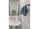 A pedestal sink vanity in a powder room features a decorative mirror, towel, and fixtures at 2501 Painted Buckeye Chase Se, Smyrna, GA 30080