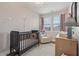 Cozy Bedroom with a dark-colored crib, comfortable chair, and a dresser near a bright window at 2501 Painted Buckeye Chase Se, Smyrna, GA 30080