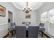 Elegant dining room featuring stylish chairs, wainscoting, a modern chandelier, and natural light from large windows at 1670 Burnt Oak Way, Dacula, GA 30019
