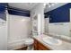 Bathroom features blue and white walls, vanity with wooden cabinets, toilet, and a tub with shower at 50 Blackberry Lane, Covington, GA 30016