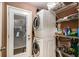 Bright laundry room with a stacked washer and dryer unit, shelving, and access to the backyard at 50 Blackberry Lane, Covington, GA 30016