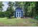 A charming blue barn-style shed with white trim adds practical storage space to the property at 50 Blackberry Lane, Covington, GA 30016