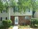 Charming townhome featuring a brick facade, complemented by well-manicured landscaping and leafy trees at 8959 Stonebridge Blvd, Douglasville, GA 30134
