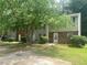 Exterior view of a townhome row, with a brick facade and siding, surrounded by mature trees and green lawns at 8959 Stonebridge Blvd, Douglasville, GA 30134