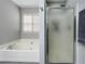 Bathroom featuring soaking tub and glass enclosed shower with gray tiling at 1361 Chatley Way, Woodstock, GA 30188