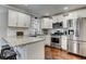 Modern kitchen with stainless steel appliances, granite countertops, white cabinets, and hardwood floors at 1361 Chatley Way, Woodstock, GA 30188