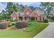 Inviting brick home with lush landscaping, including bushes and trees, and a well-maintained front lawn at 3217 Aberrone Pl, Buford, GA 30519