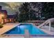 Backyard pool featuring diving board and slide surrounded by a large patio and mature trees at twilight at 3217 Aberrone Pl, Buford, GA 30519