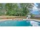 Inviting in-ground pool with a slide and stone firepit area, surrounded by a wooden fence and trees at 3217 Aberrone Pl, Buford, GA 30519
