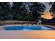 Inviting pool with a slide and fire pit surrounded by lush trees, perfect for evening relaxation and summer entertainment at 3217 Aberrone Pl, Buford, GA 30519