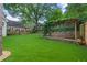 A spacious, well-manicured backyard with artificial turf, a stone retaining wall, and a covered patio at 480 Wimbledon Ne Rd, Atlanta, GA 30324