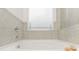 A closeup of a white bathtub surrounded by neutral toned ceramic tile at 939 Brittfield Way, Loganville, GA 30052