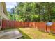A view of a backyard with a small patio, grass, trees and a wooden fence at 3192 Spicy Cedar Lane Ln, Stonecrest, GA 30038