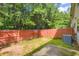 A view of a backyard with a small patio, grass, trees and a wooden fence at 3192 Spicy Cedar Lane Ln, Stonecrest, GA 30038