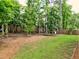 Expansive backyard with a mix of grass and pine straw, enclosed by wood and wrought iron fences with a doghouse at 913 Sunny Meadows Ln, Marietta, GA 30062