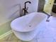 Close up of a modern freestanding bathtub with sleek fixtures and marble tile at 913 Sunny Meadows Ln, Marietta, GA 30062