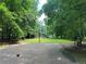 Outdoor basketball court with playground and bench surrounded by lush green trees at 4300 May Apple Dr, Alpharetta, GA 30005