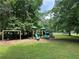 Community playground with slides and swings surrounded by a lush green lawn at 4300 May Apple Dr, Alpharetta, GA 30005