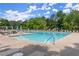 Large community swimming pool with lounge chairs and tables in a fenced in area on a sunny day at 4300 May Apple Dr, Alpharetta, GA 30005