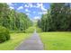Scenic paved walking path through a grassy area with tall trees on either side leading into the distance at 4300 May Apple Dr, Alpharetta, GA 30005