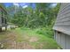 Spacious backyard with a storage shed, lush trees and an elevated deck in the distance at 5242 Mccarter Sta, Stone Mountain, GA 30088