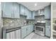Well-equipped kitchen with stainless steel appliances, gray cabinetry, tile backsplash, and granite countertops at 5242 Mccarter Sta, Stone Mountain, GA 30088