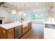 Open kitchen with large island, stainless appliances, hardwood floors and adjacent room with brick fireplace at 6525 Rhett Run, Cumming, GA 30028