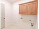 Laundry room featuring sleek wooden cabinets, bright tile flooring, and utility connections at 6525 Rhett Run, Cumming, GA 30028