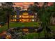 Expansive backyard at dusk with lush greenery, a charming pond, and a spacious deck, illuminated by exterior lights at 1865 Mason Mill Rd, Decatur, GA 30033
