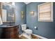 Stylish half bath with a wood vanity, dark countertops, blue walls, and natural light at 4275 Green Summers Dr, Cumming, GA 30028