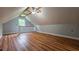 Spacious attic room featuring wood-look flooring, a window, a ceiling fan, and natural light at 6109 N Main Se St, Acworth, GA 30101