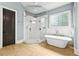 Bathroom with glass enclosed shower, soaking tub, tile floors, and dark wood door at 5114 Brendlynn Dr, Suwanee, GA 30024