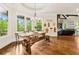 Bright dining room with large windows, hardwood floors, and a modern rustic wooden table and bench set at 5114 Brendlynn Dr, Suwanee, GA 30024