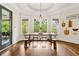 Elegant dining area with natural light, hardwood flooring, a rustic table, and views of green landscaping at 5114 Brendlynn Dr, Suwanee, GA 30024