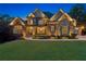 Stunning two-story home featuring stone and brick facade, lush landscaping, and inviting front lawn at twilight at 5114 Brendlynn Dr, Suwanee, GA 30024